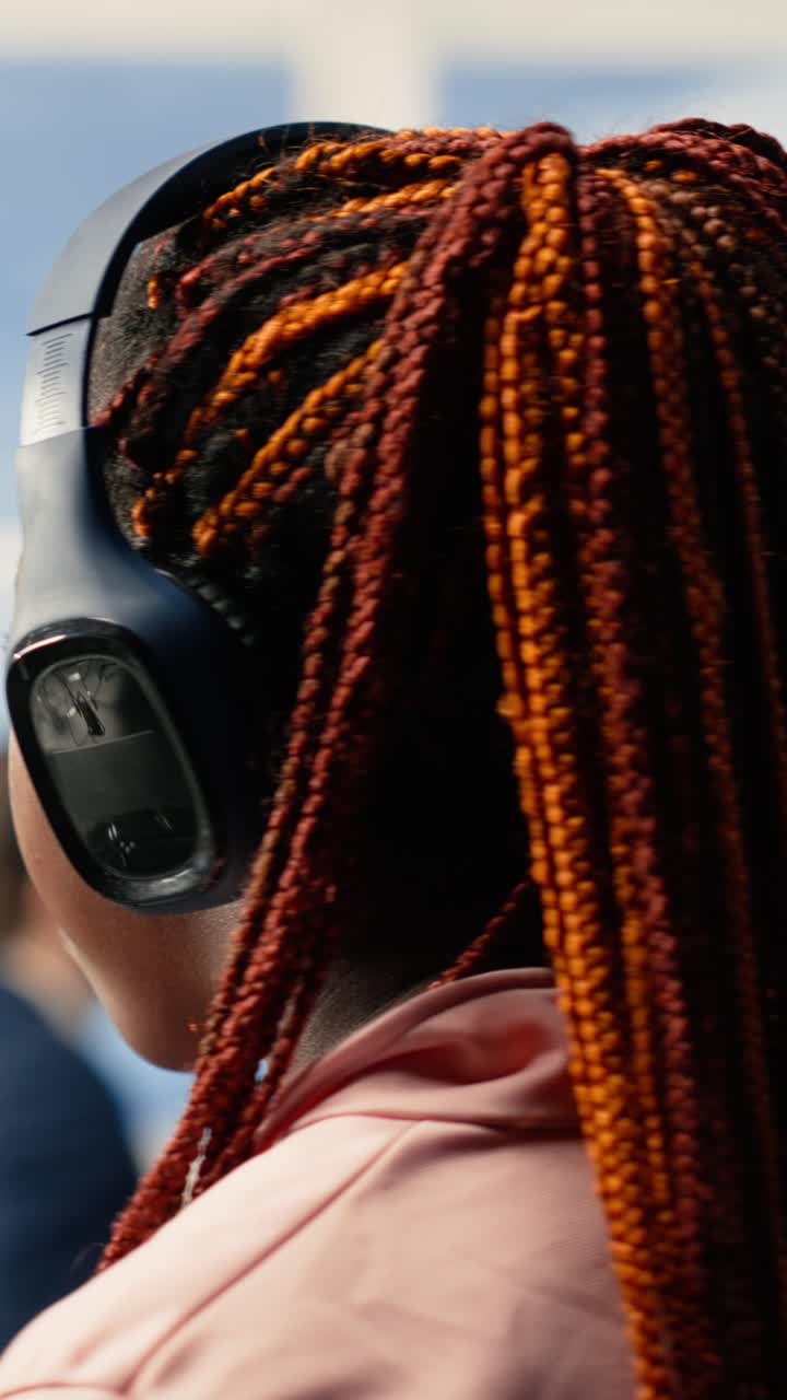 Vista posteriore di donna con capelli intrecciati che indossa cuffie.