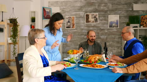 woman bringing roasted chicken to the table at family dinner