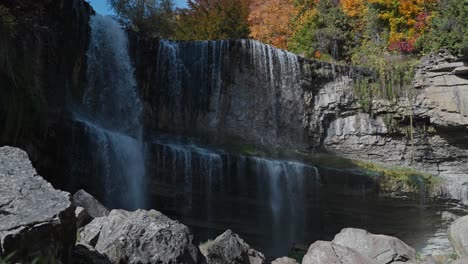 autumn waterfall cascading over rocky cliffs surrounded by colorful fall foliage