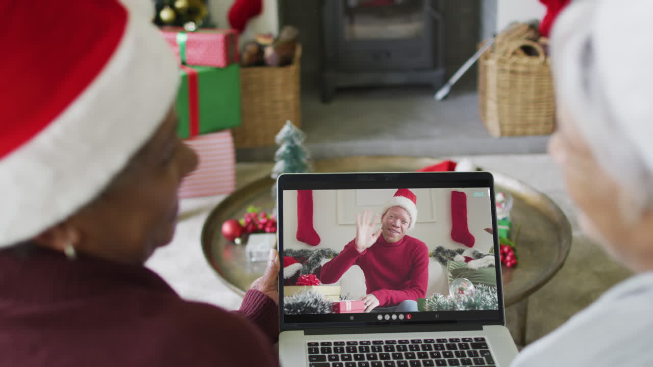 amigas mayores diversas usando una computadora portátil para una videollamada de navidad con una amiga sonriente en la pantalla