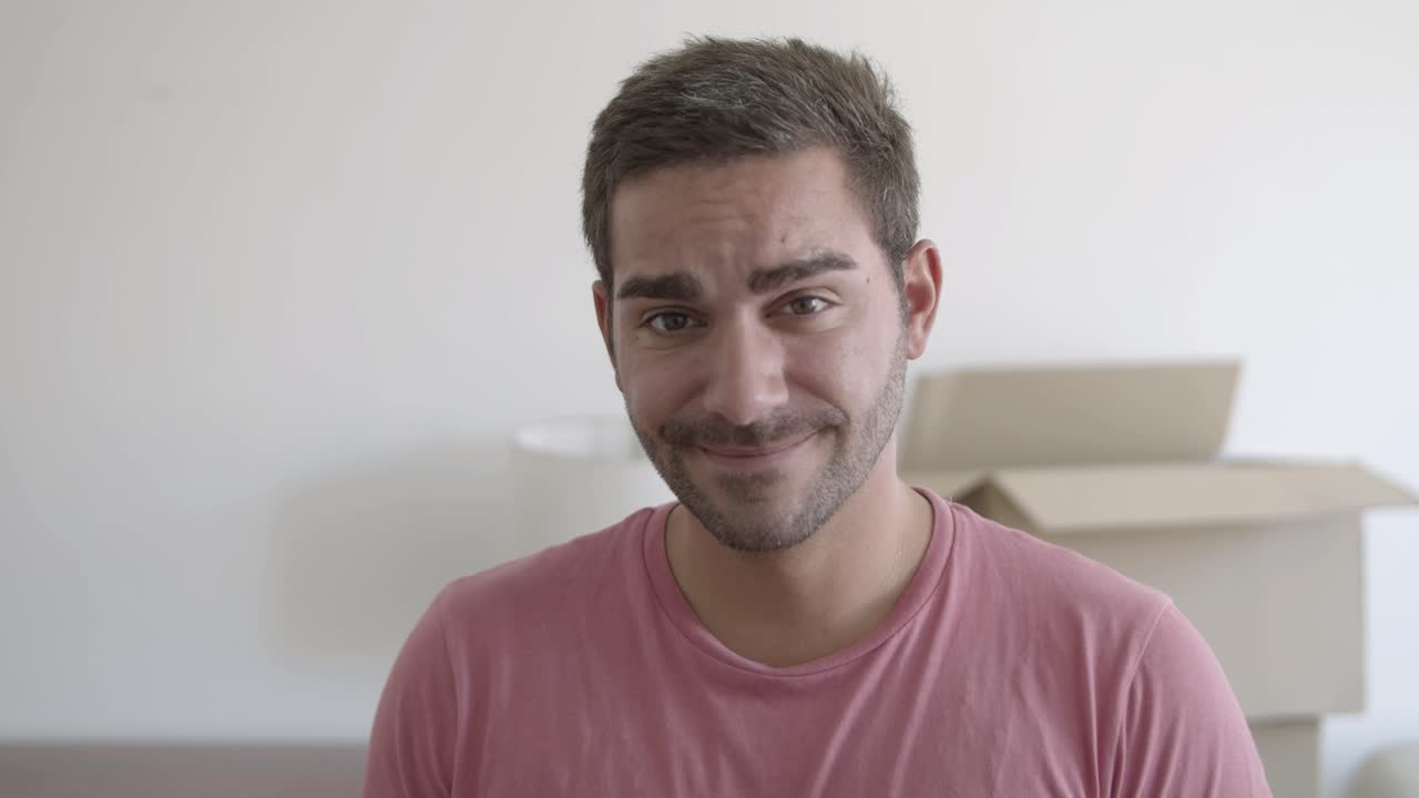 retrato de un joven feliz parado en la sala de estar de su nueva casa y sonriendo a la cámara