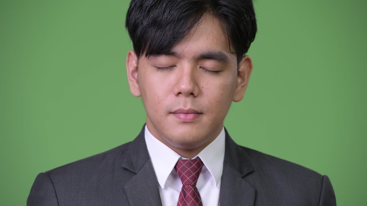 젊은 잘생긴 아시아 사업가 눈을 감고 휴식을 취하고 있습니다.