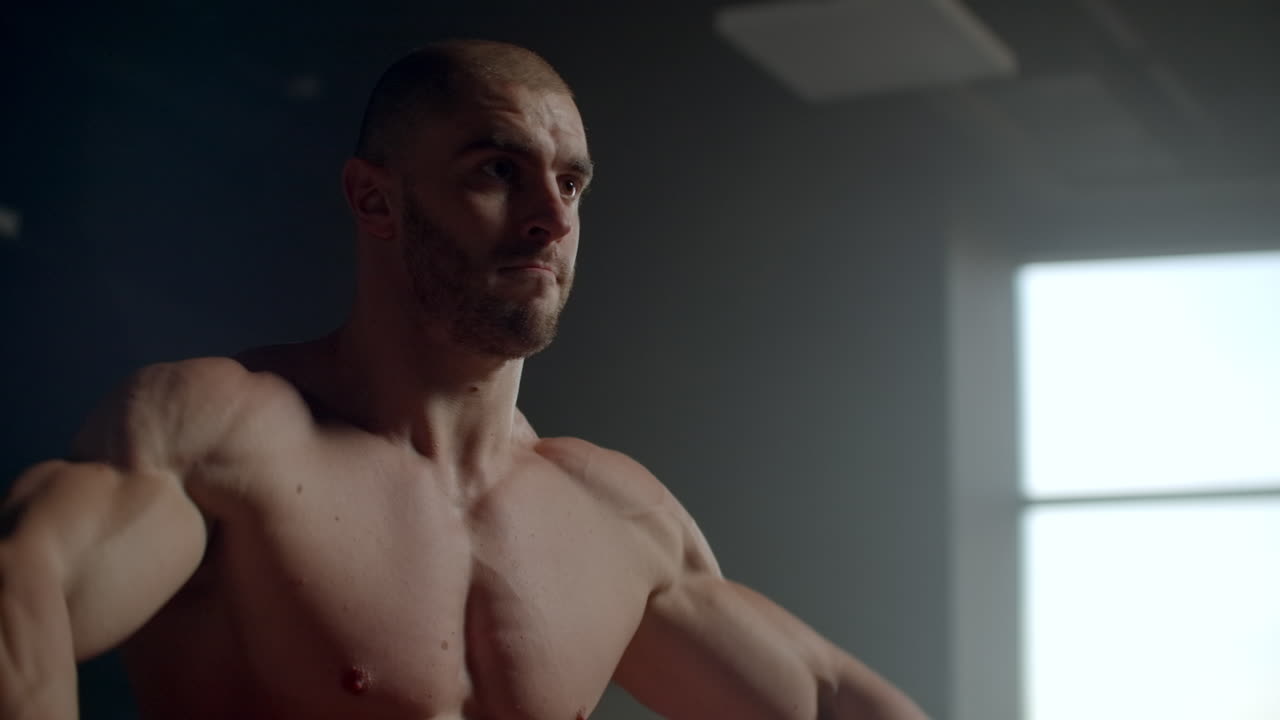 hombre brutal levanta pesas en el gimnasio entrenando su espalda y hombros. hermoso club de fitness con grandes ventanas. entrenamiento poderoso con pesas y levantamiento de pesas en pesas