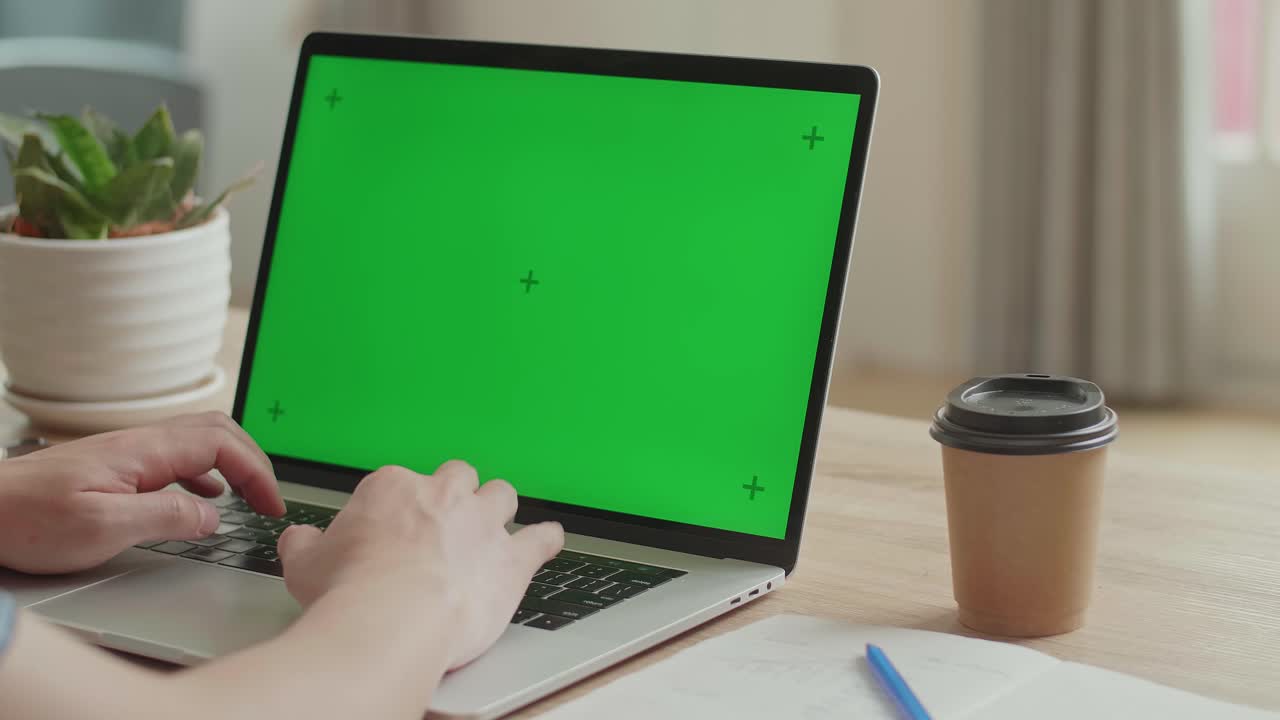 Hands Typing On Laptop Keyboard With Green Mock-Up Screen While Sitting At The Desk, Video In 4K