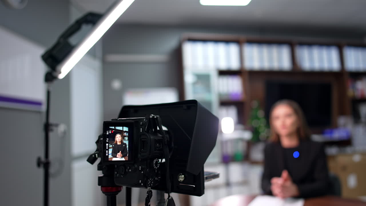Camera records a female blogger sitting in the office. Close up. Professional equipment filming video for blog or YouTube channel.