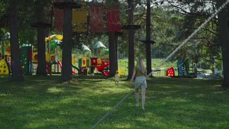 Woman-follows-son-walking-to-playground-in-old-pine-forest