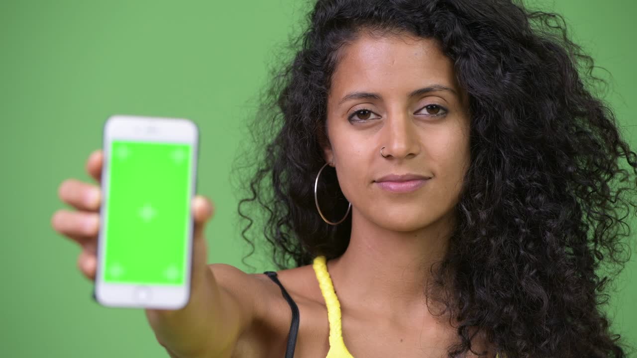 Young beautiful Hispanic woman showing phone