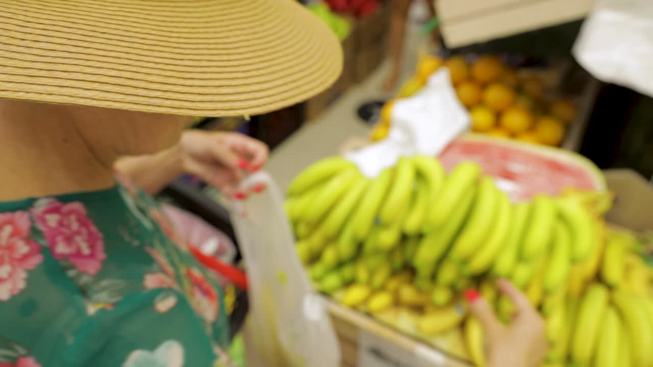 dama con sombrero recogiendo plátanos en el mercado