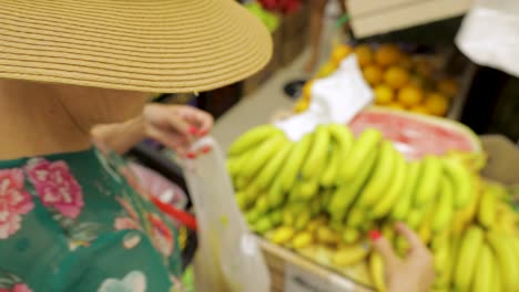 Dame-Mit-Hut,-Die-Bananen-Auf-Dem-Markt-Pflückt