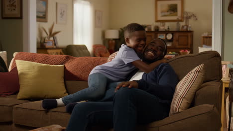 a father and son share a warm hug on a couch in their living room