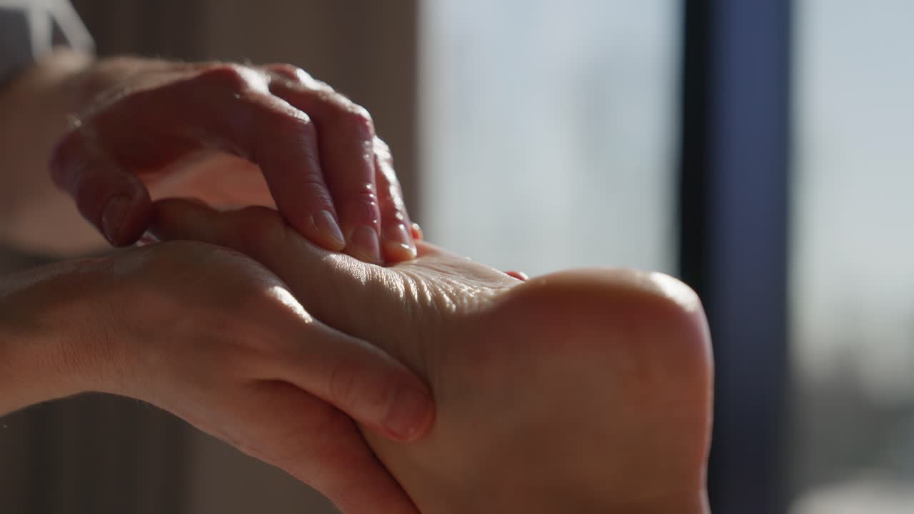 Gros plan sur des mains massant un pied avec de l'huile