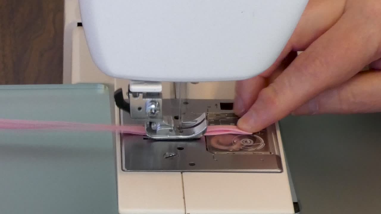 A woman top-stitches narrow strips of binding