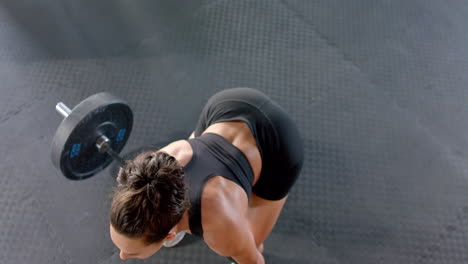 lifting barbell, woman in gym performing deadlift exercise for strength training