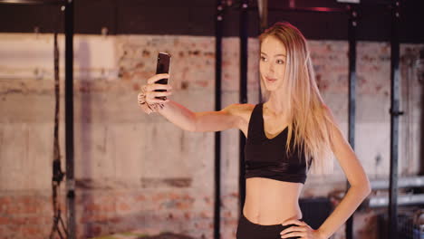 Schöne-Sportlerin,-Die-Haare-Anpasst,-Während-Sie-Im-Gesundheitsstudio-Ein-Selfie-über-Das-Smartphone-Macht