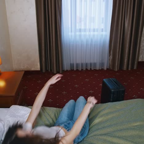 tired woman after packing suitcase. young woman puts packed luggage and falling down on bed in comfortable hotel room. the end of a trip