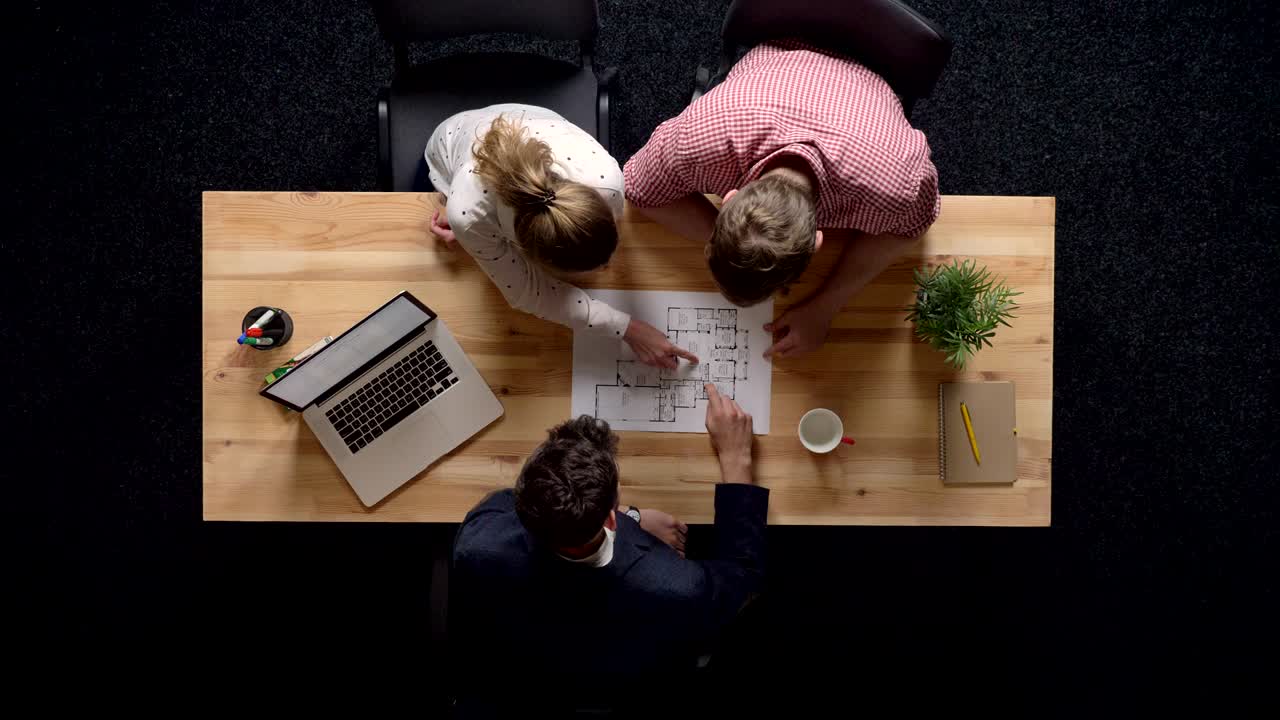 To kunder diskuterer detaljer om byggeplan med udvikler, kommunikationskoncept, arbejdskoncept, topbillede