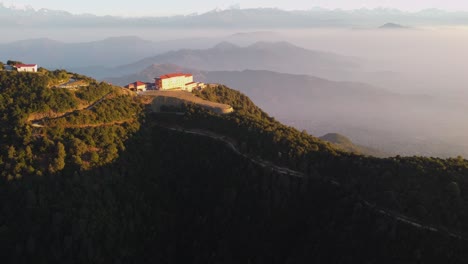 kathmandu, nepal - december 12, 2021: an aerial view of a resort perched on a hilltop with the himalayan mountain range in the background