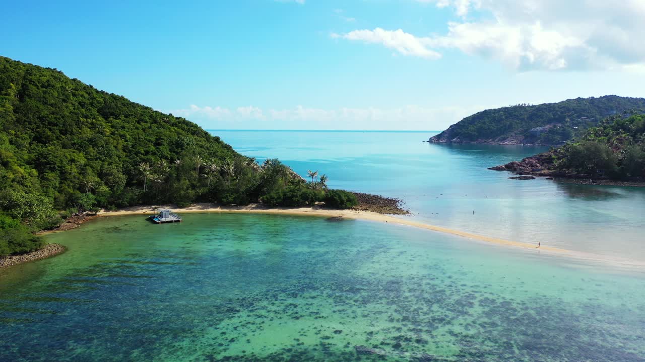 Beautiful lagoon with coral reefs under calm clear water near rocky coast of tropical island with lush vegetation in Thailand