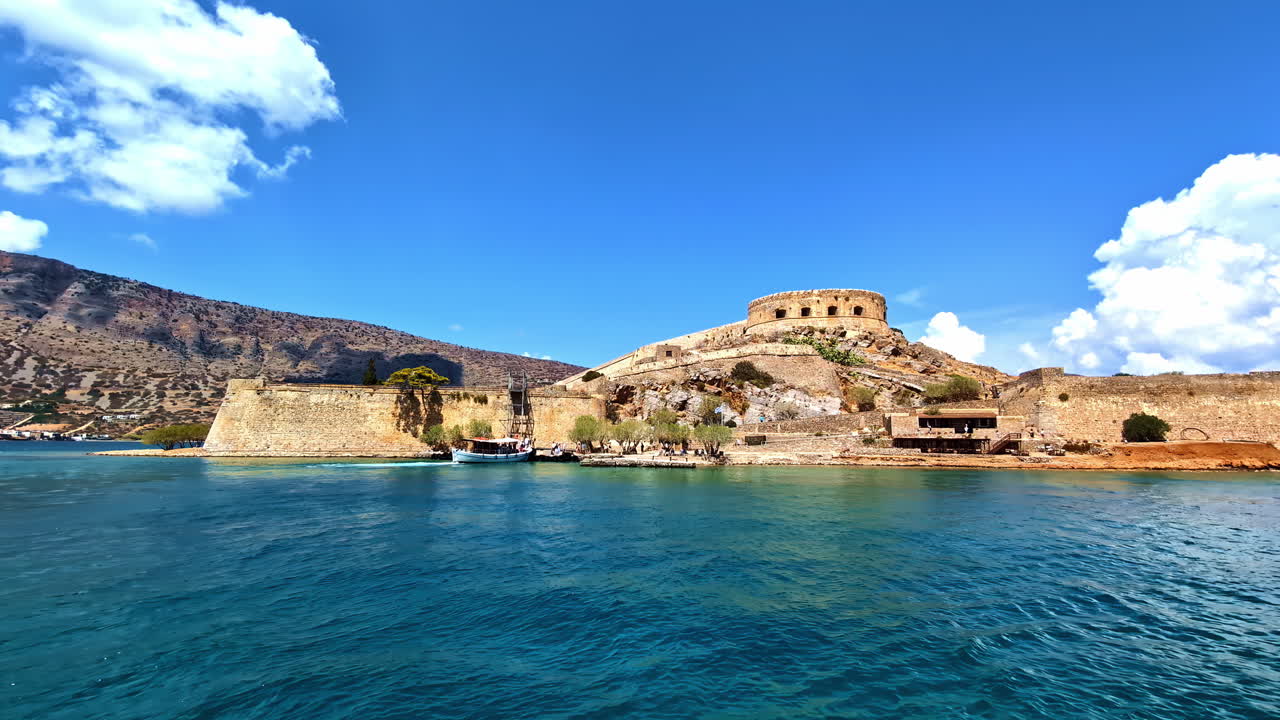 Establishing shot of Spinalonga Fortress on Crete Island, Greece, capturing the historic structure and surrounding blue waters