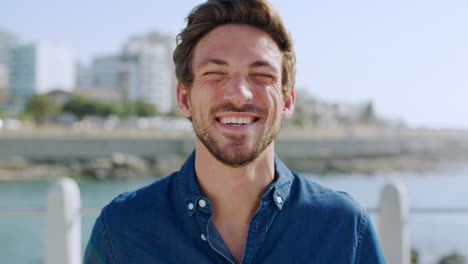 feliz, sonrisa y rostro de hombre en la playa para viajar