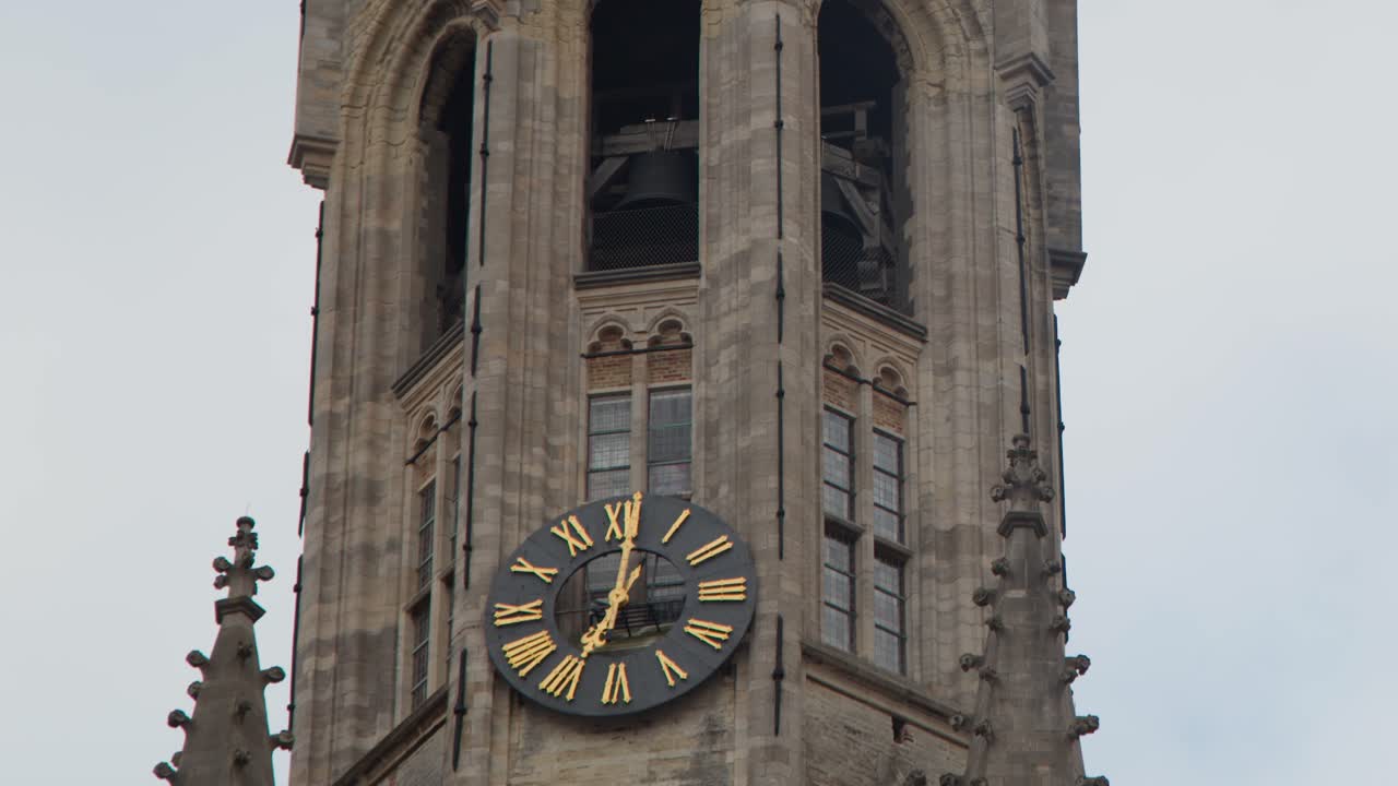 Camera tilts upward along historic bell tower with clock, overcast daylight, steady movement, architectural focus