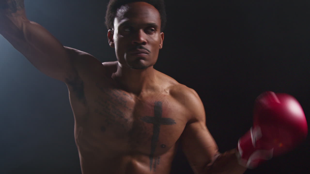 boxeador tatuado con guantes entrando en el ring antes del comienzo del partido de boxeo saludando y saludando a los fanáticos