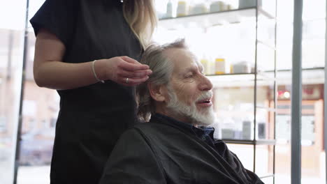 hombre mayor discutiendo corte de pelo con estilista femenina en un salón de peluquería