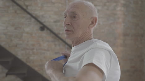 old man using a stretching band and exercising at home 2