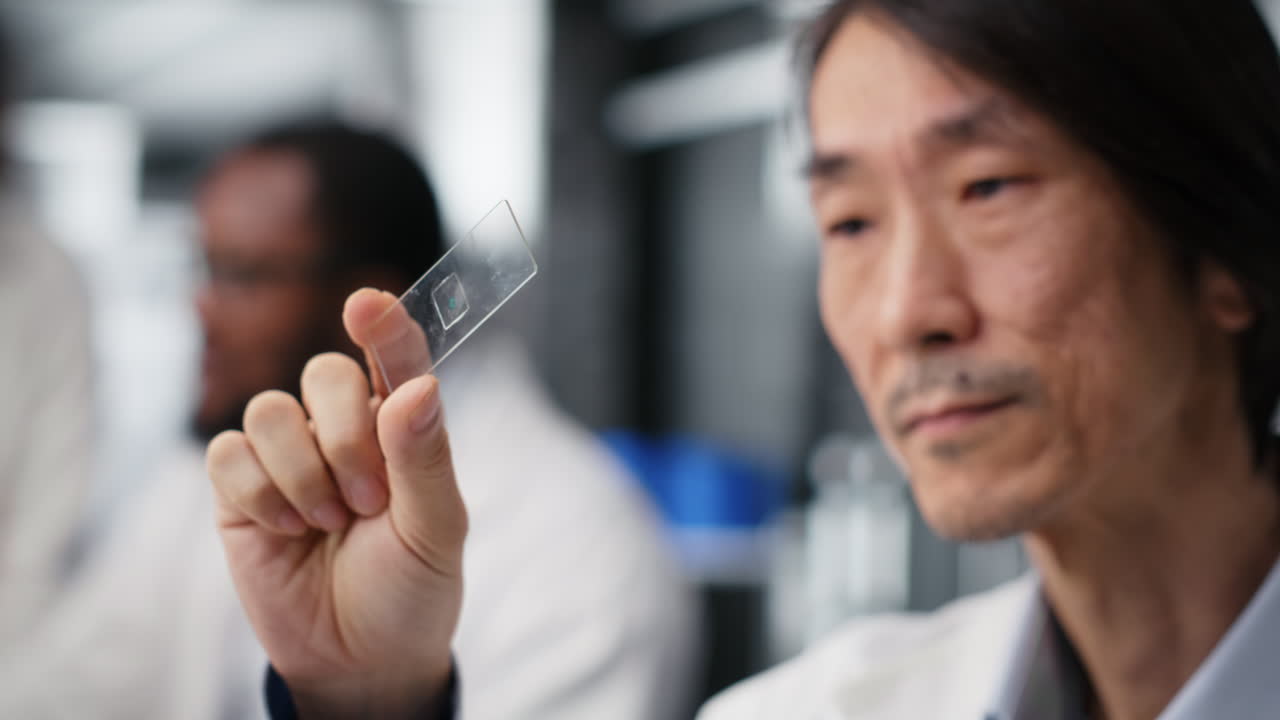 Vertical video Senior microscopist examining microscope glass slide in laboratory