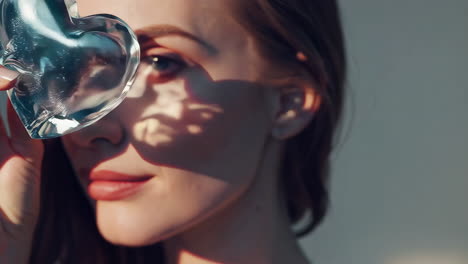 close-up of a woman holding a clear heart with light and shadow effects