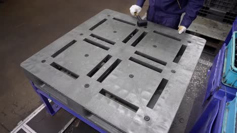 recycled plastic pallet handling, factory worker inspecting, industrial setting, stacking plastic pallets.