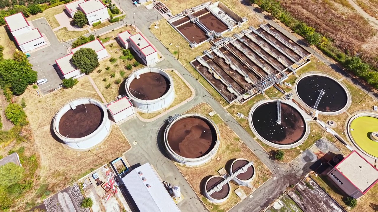 Water treatment facility in operation during daylight showing large tanks and processing areas with equipment in use