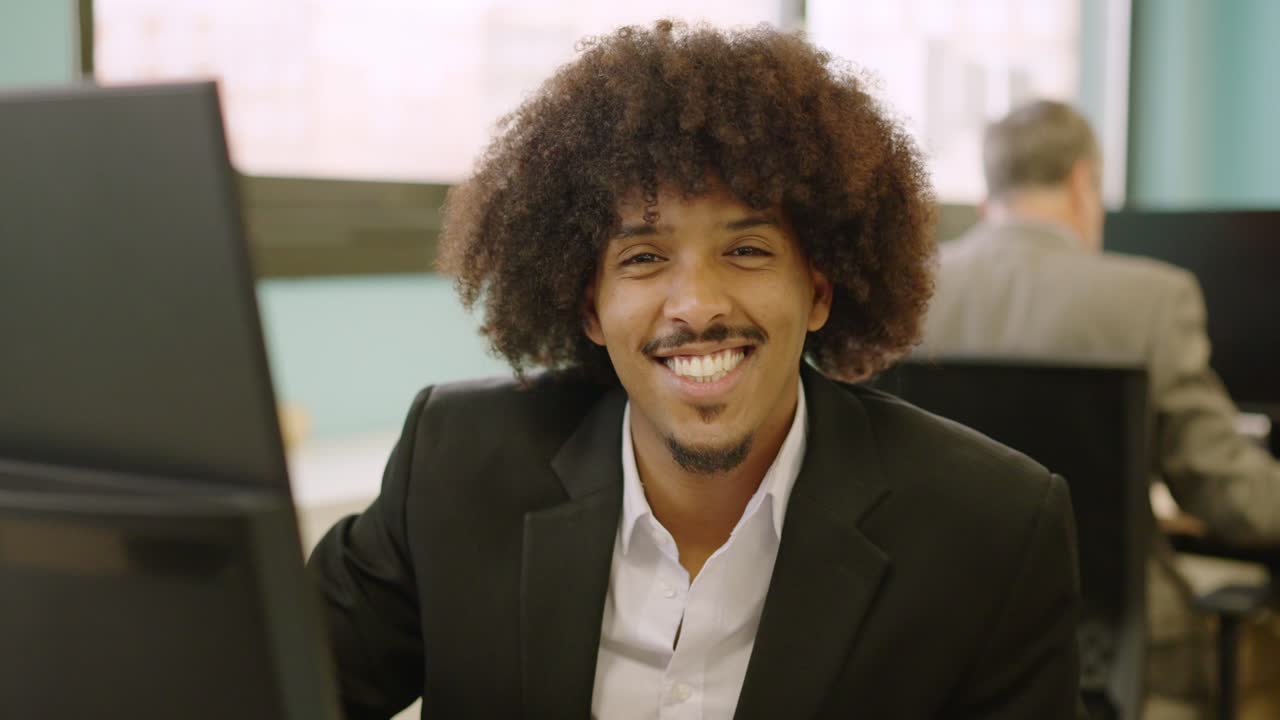 African american man smiling at camera while working in coworking