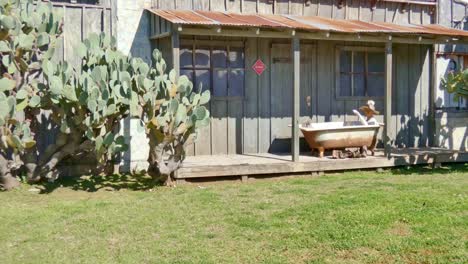 cowboy-in-bath-tub-out-side-old-western-style-cabin-scene-form-gold-rush-days