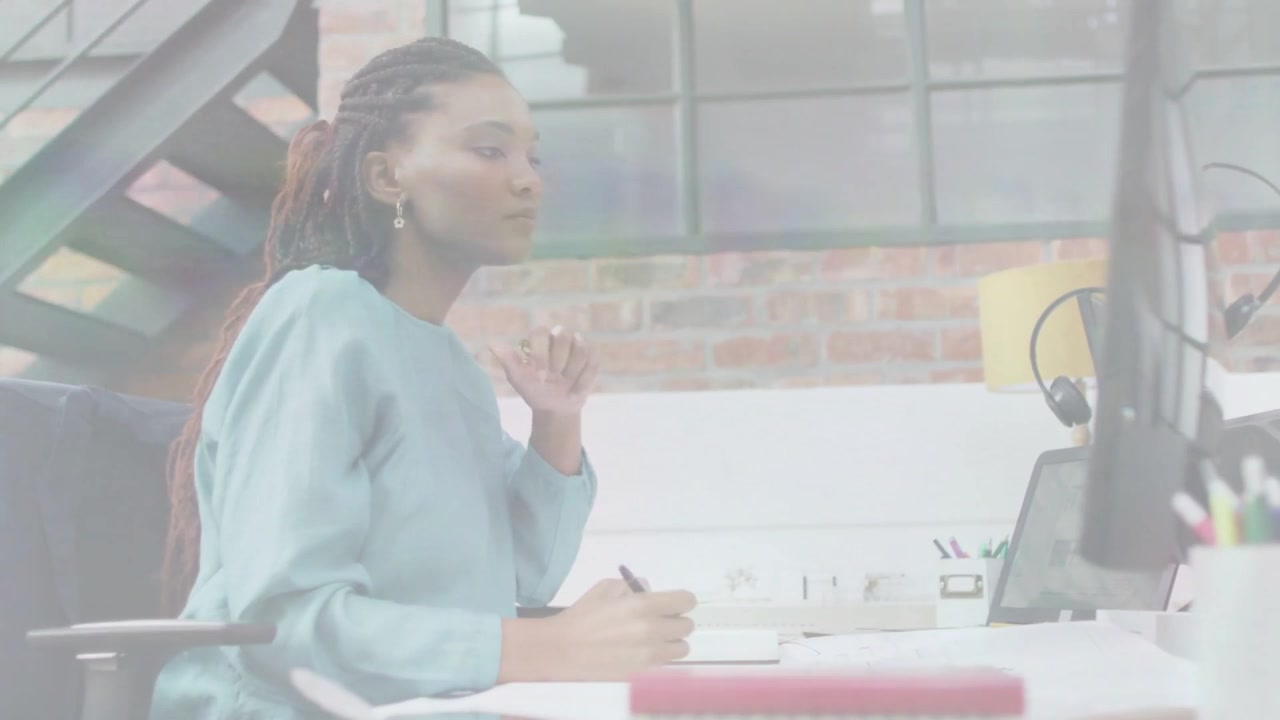 Video verticale: Donna con top color ottanio che guarda un monitor e scrive su un quaderno in un loft.