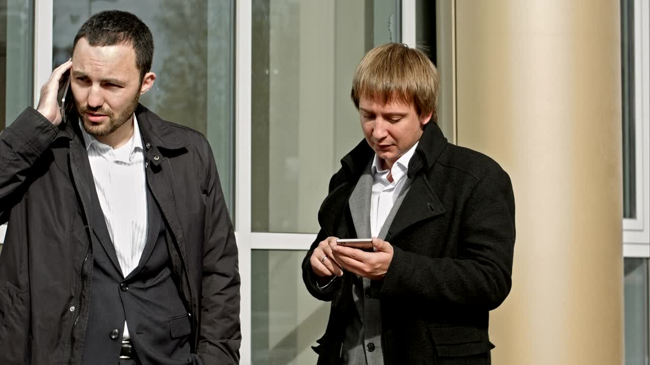 두 사업가 가 드폰 으로 대화 하고 메시지 를 읽고 있다