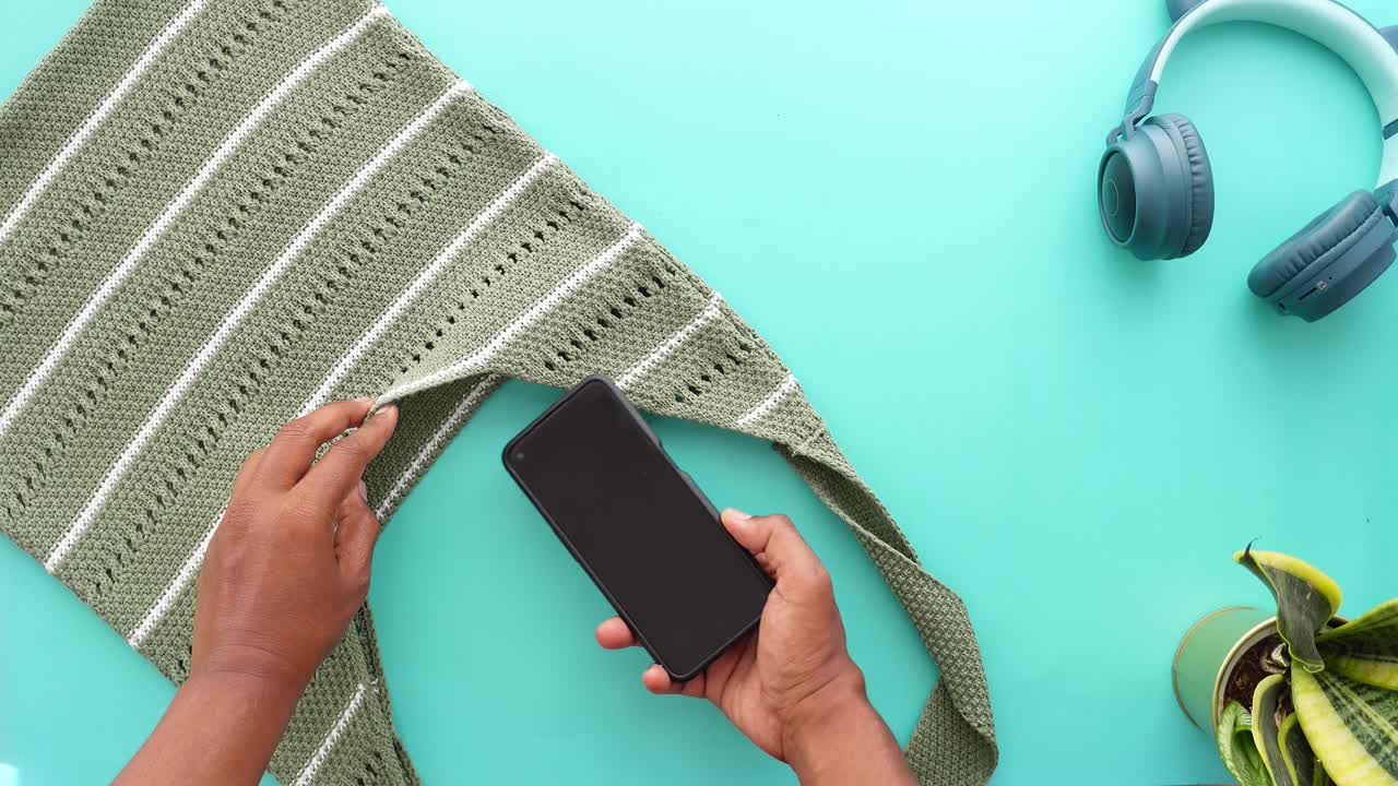 Overhead shot of a smartphone, bag, headphones, and plant