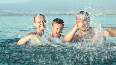 family of three splashing water in sea