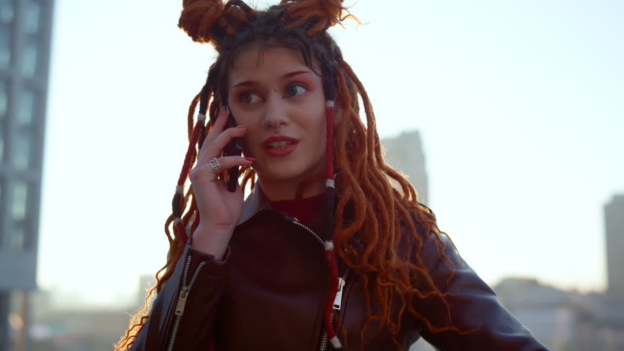 Smiling ginger woman using cellphone outdoor. Focused girl speaking mobile phone