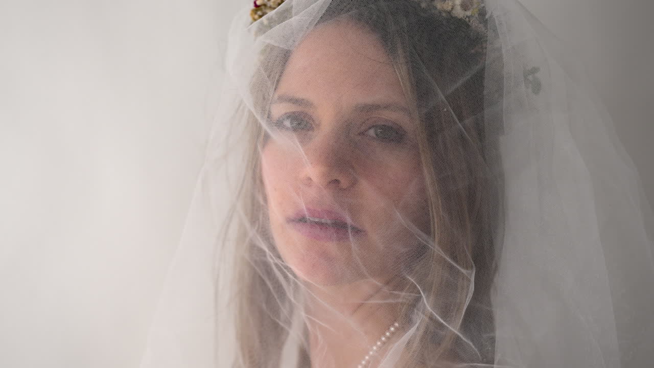 La telecamera si avvicina alla sposa mentre lei si gira lentamente per guardarla. Il suo sguardo neutro aggiunge un senso di calma e compostezza, creando un momento intimo e sereno.