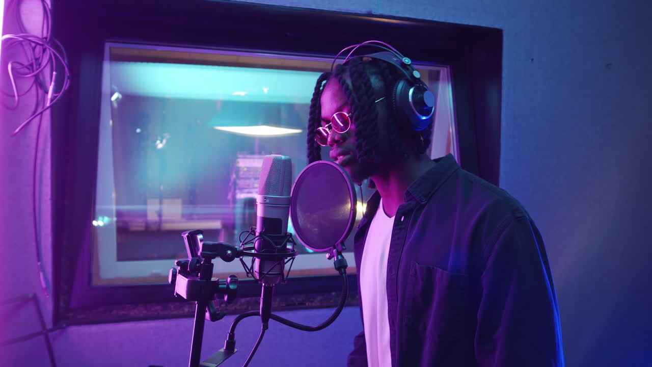 Rapper afroamericano che canta al microfono in uno studio di registrazione