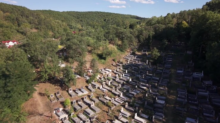 Un drone sorvola file di tombe su una collina boscosa a Săvădisla, in Romania