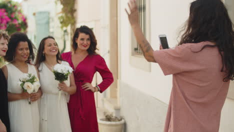 girl taking picture of lesbian couple with friends at wedding