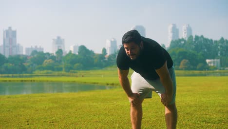 Young-man-tired-catching-his-breath-after-exercising-at-a-beautiful-park