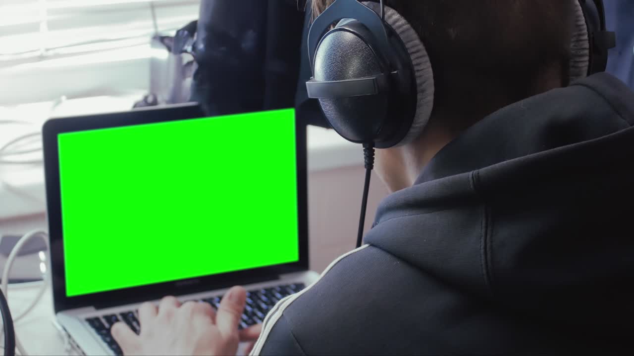 hombre con auriculares con una pantalla verde