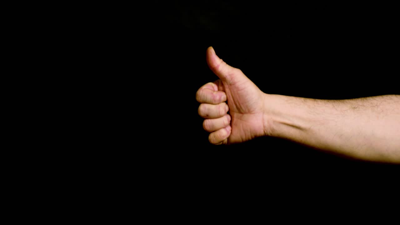 Male hand showing thumbs up on black background