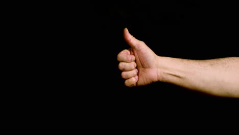 male hand showing thumbs up on black background