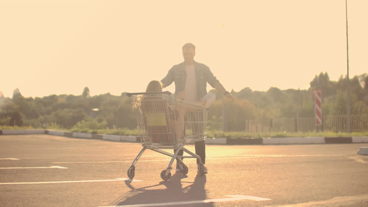 Young friends having fun on shopping trolleys. Multiethnic young people racing on shopping cart. slow motion