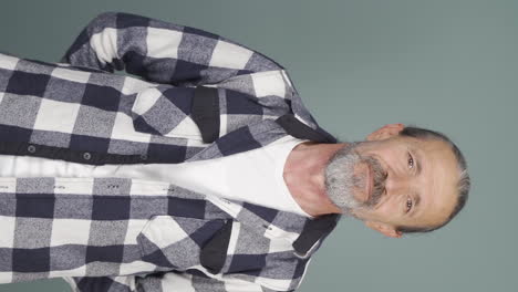 Vertical-video-of-Old-man-making-stop-sign-for-camera.