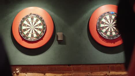 dos jugadores lanzando dardos durante un partido de dardos
